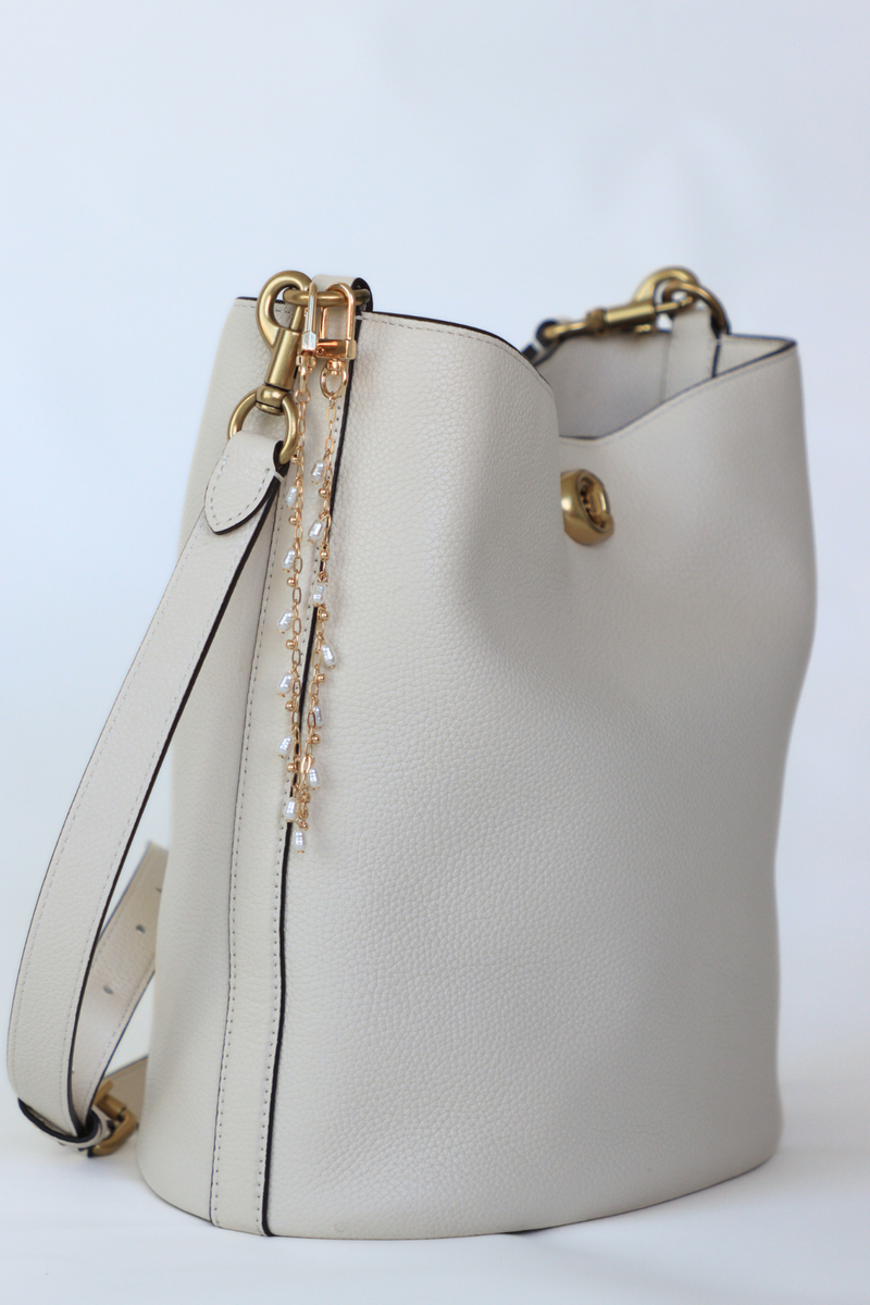 White handbag with gold accents on a light gray background