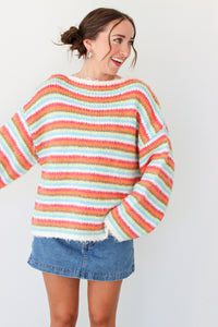 Woman wearing a multi color striped sweater with a denim mini skirt 