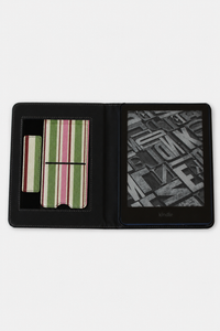 A black faux-leather e-reader case shown open on a light gray background, featuring a striped card holder on the left and a black-and-white book page displayed on the screen on the right.