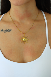 woman wearing a gold sun necklace 