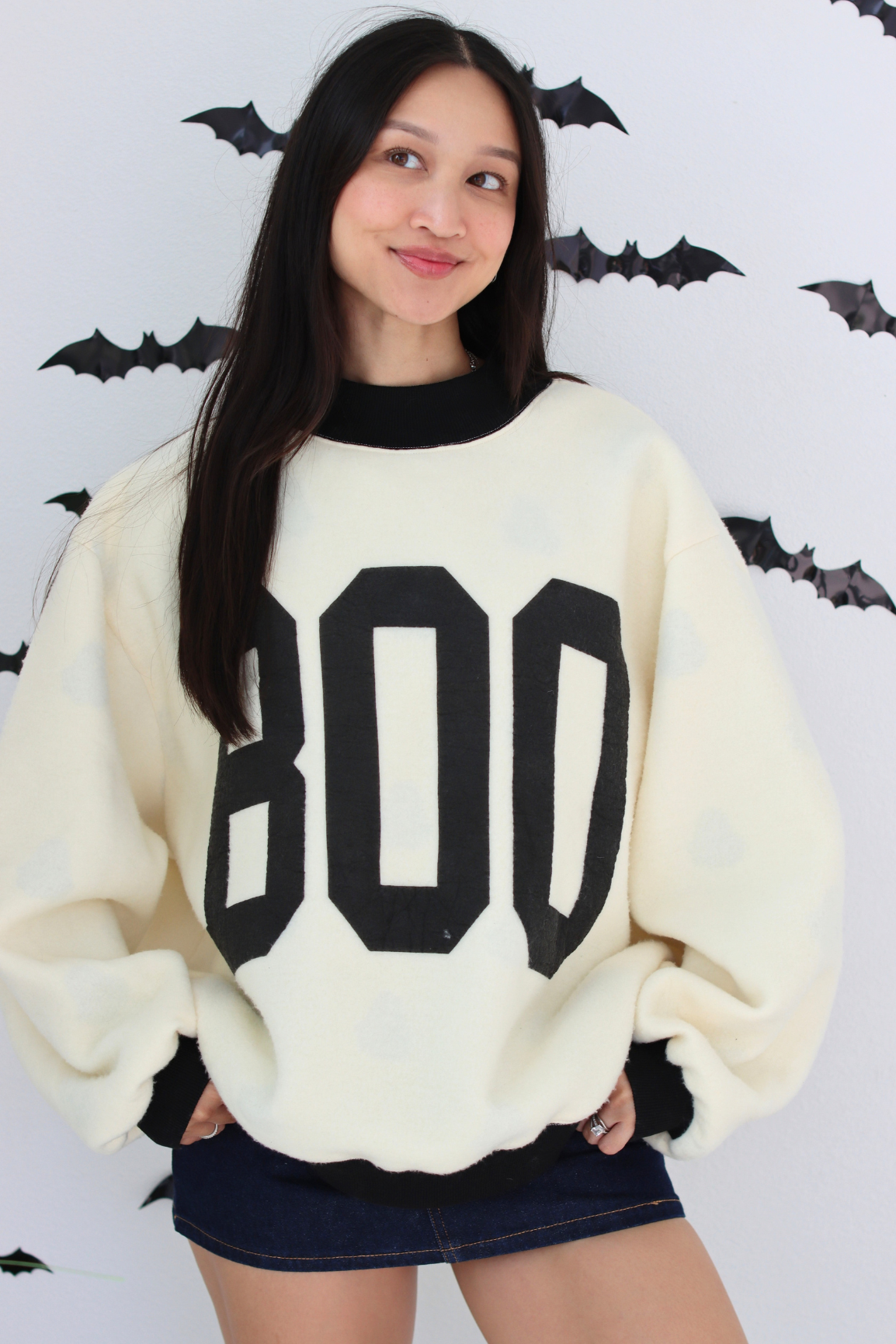 Woman wearing a white sweater with BOO graphic 