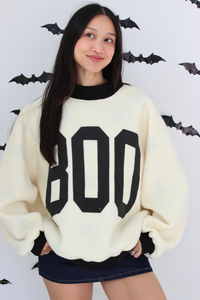Woman wearing a white sweater with BOO graphic 
