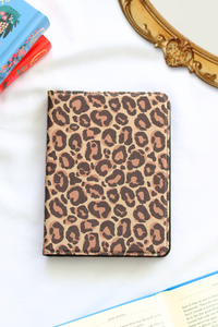 Leopard print kindle on a white surface with books in the background
