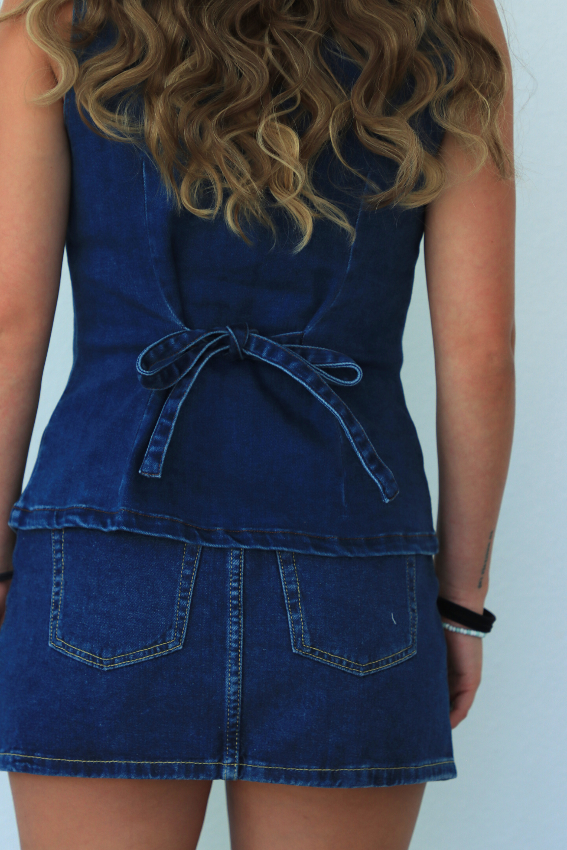 Person wearing a blue denim dress against a white background