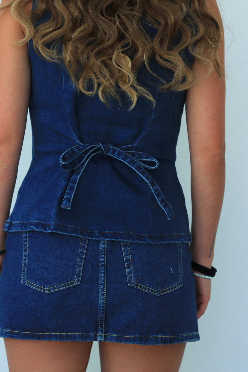 Person wearing a blue denim dress against a white background