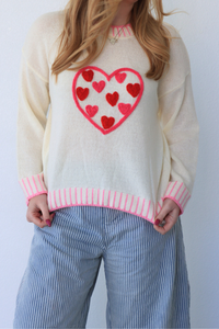 girl wearing cream sweater with pink heart detailing