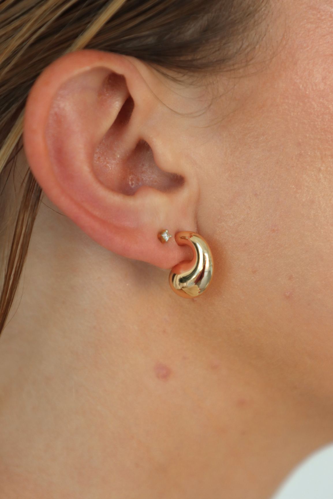 Close-up of an ear wearing a gold hoop earring.