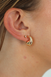 Close-up of an ear wearing a gold hoop earring.