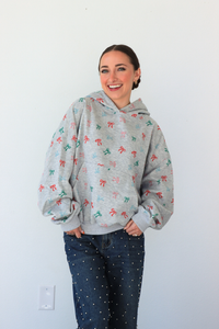 Woman wearing a gray hoodie with colorful patterns against a white wall