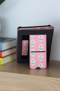 Black and pink patterned case on a wooden surface with books in the background