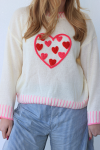 girl wearing cream sweater with pink heart detailing