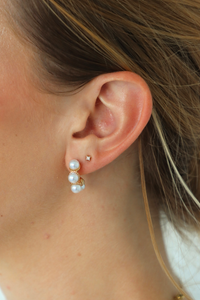 Close-up of an ear wearing a pearl earring with a blurred background