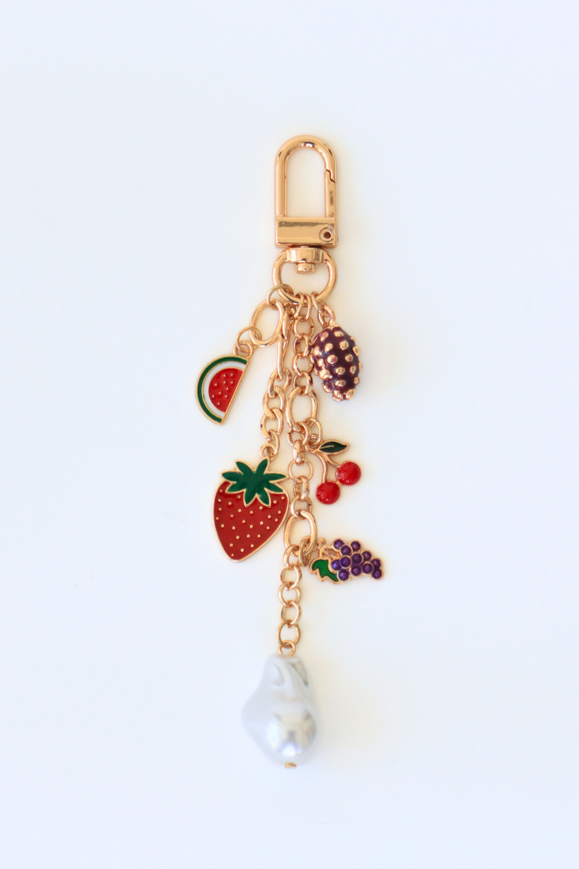 Gold keychain with fruit-themed charms on a white background