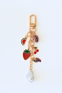 Gold keychain with fruit-themed charms on a white background