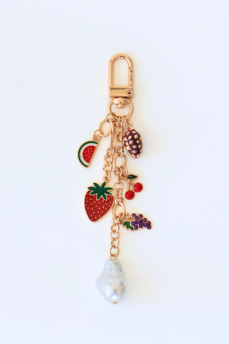Gold keychain with fruit-themed charms on a white background