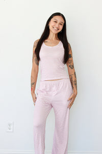 Woman wearing a pink striped tank and pant pajama set 
