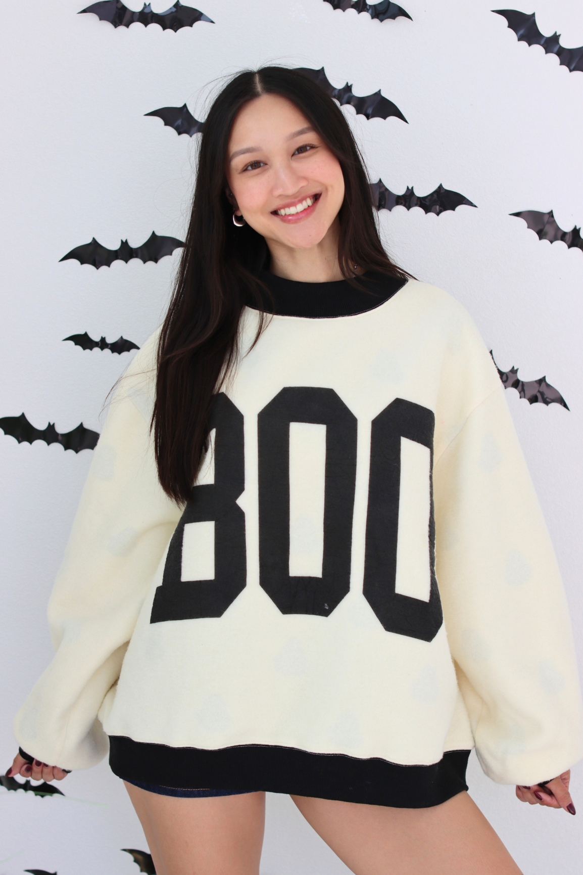 Woman wearing a white sweater with BOO graphic 