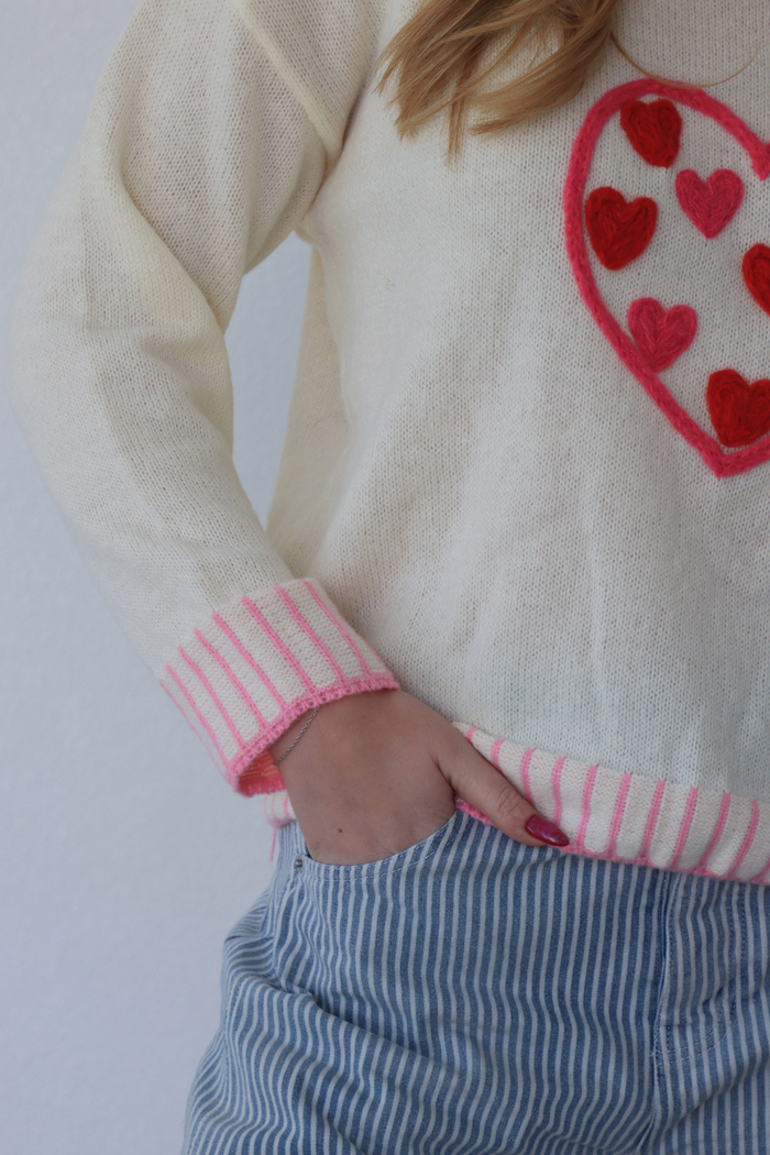 girl wearing cream sweater with pink heart detailing