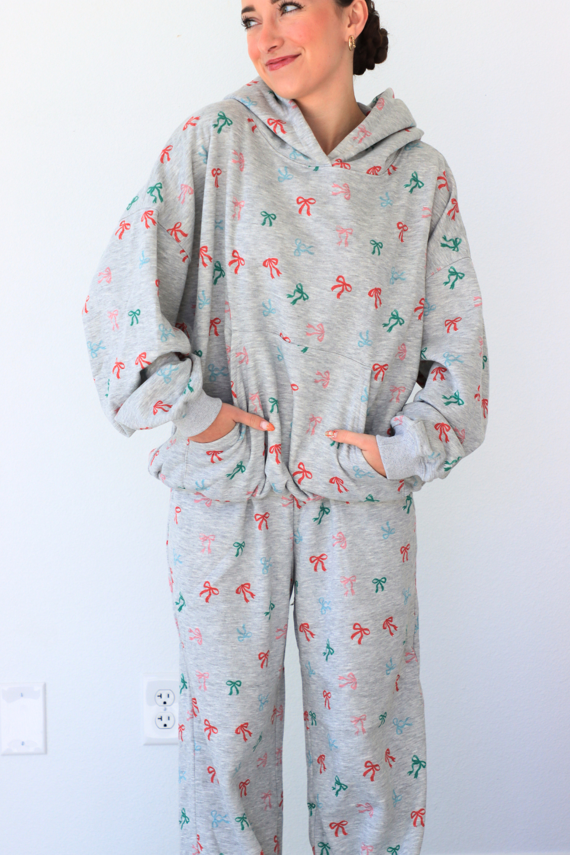 Person wearing a gray hoodie and pants with colorful patterns on a white background