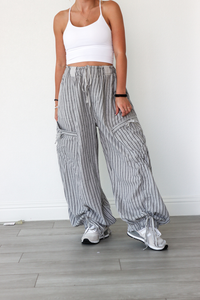 Person wearing a white crop top and gray striped wide-leg pants on a light wooden floor.