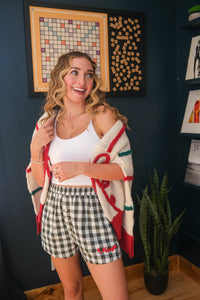 girl wearing plaid pajama shorts with "merry" embroidering