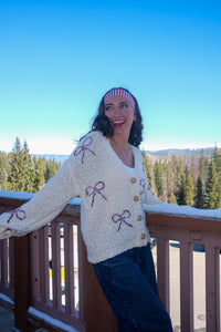 Woman wearing a cream cardigan with bow patterns