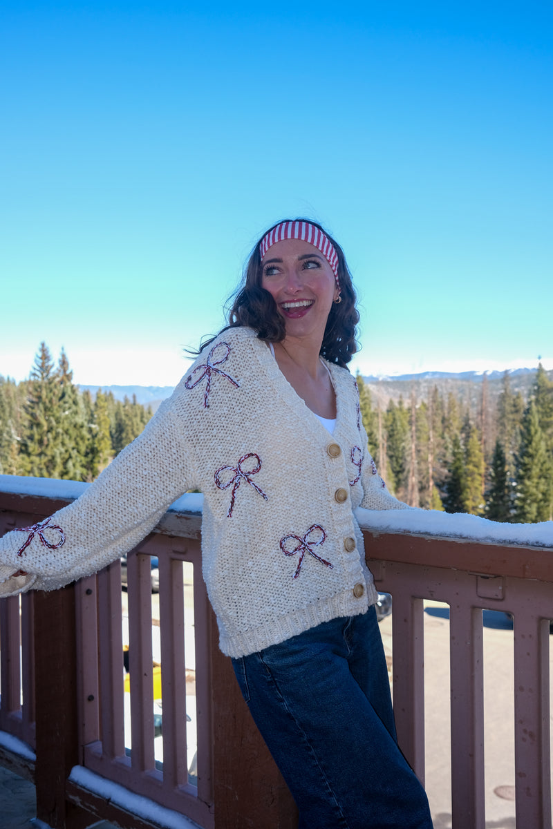 Woman wearing a cream cardigan with bow patterns