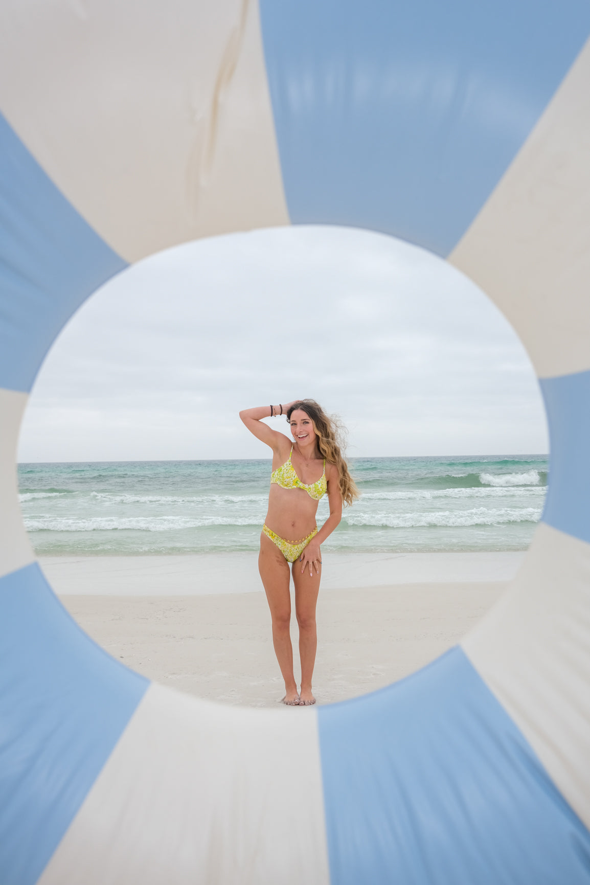 Woman in a yellow bikini standing on a beach with a circular design in the foreground
