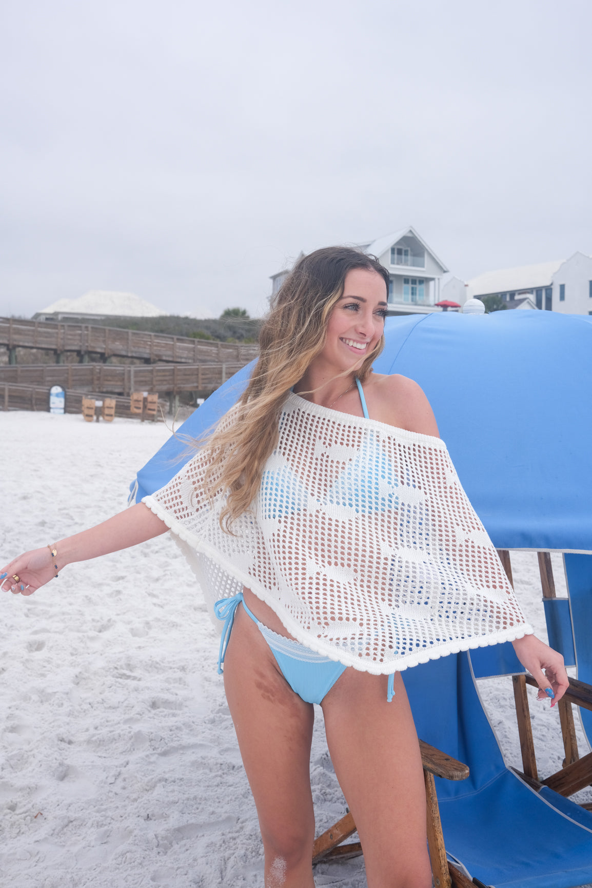 Woman on a beach with a blue umbrella and white sand