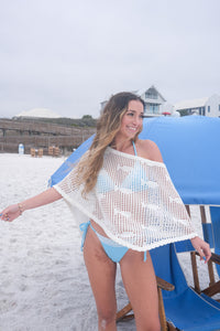 Woman on a beach with a blue umbrella and white sand