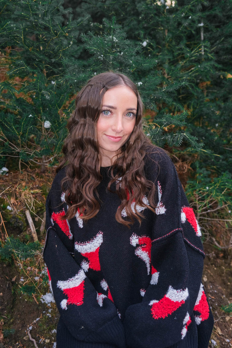 girl wearing black sweater with red santa hat pattern