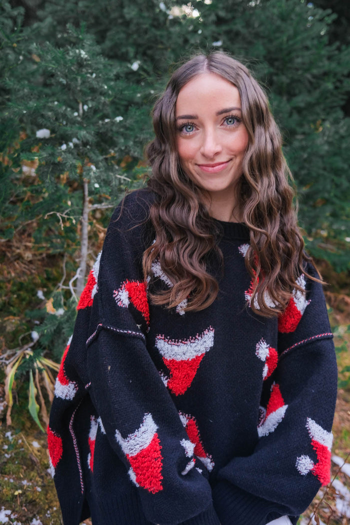 girl wearing black sweater with red santa hat pattern