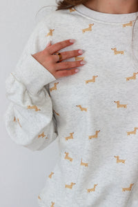 Light gray sweatshirt with small dog prints worn by a person on a light gray background