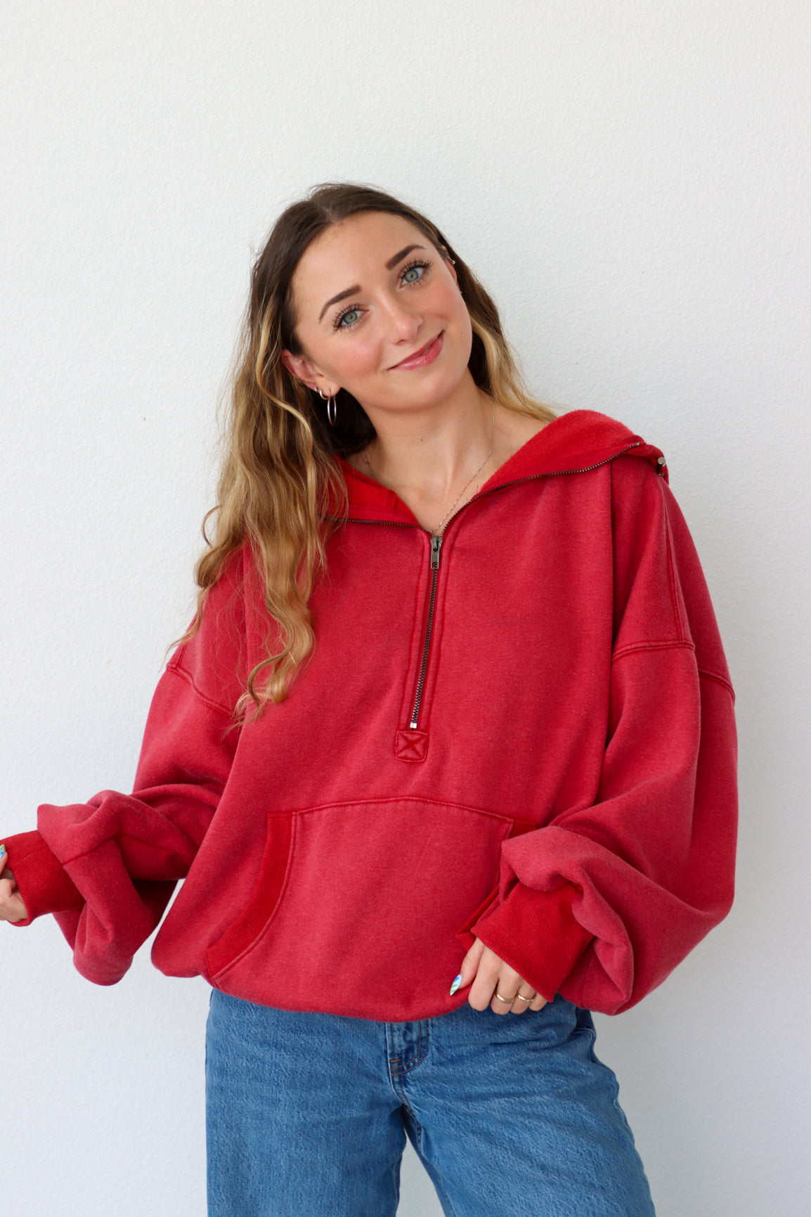 Woman wearing a red pullover with a zipper against a white background