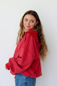 Woman wearing a red hoodie and blue jeans against a white background