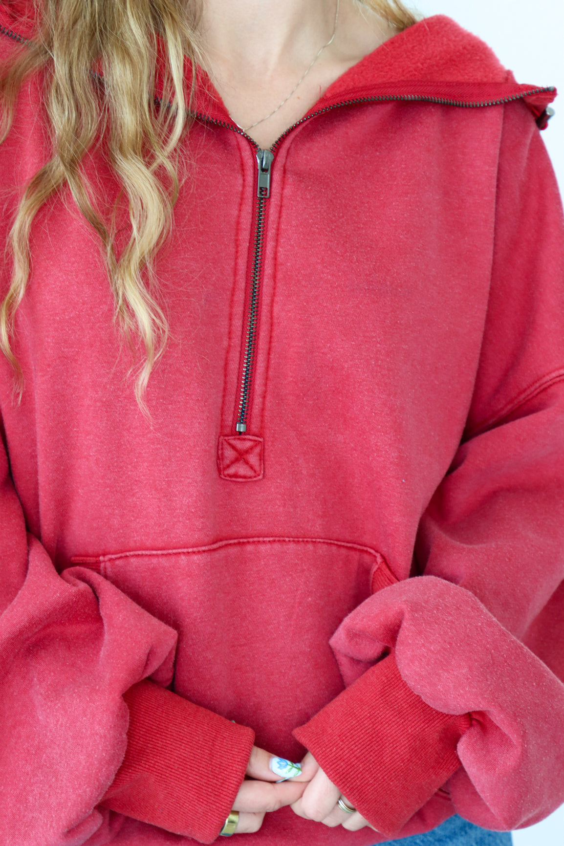 Red pullover with a quarter zip worn by a person, with a focus on the chest area.