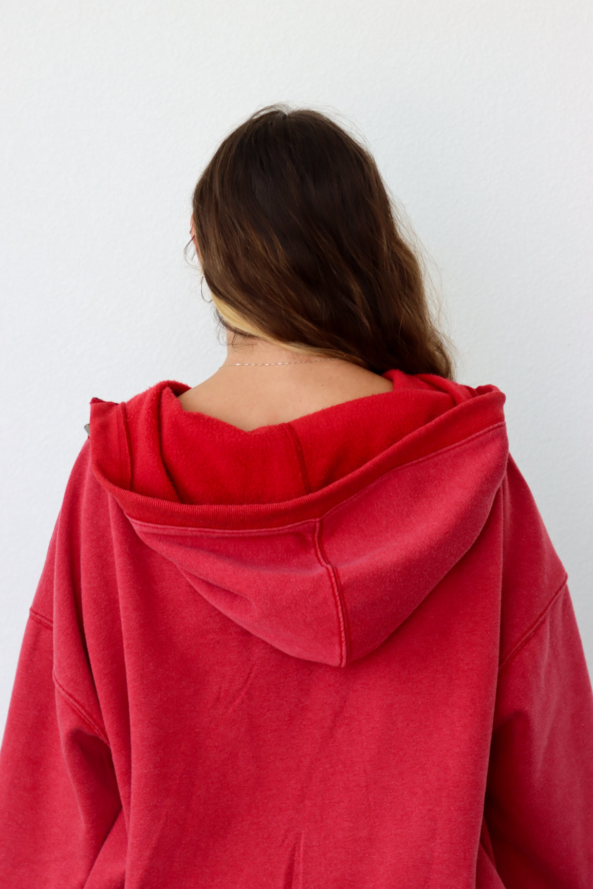 Person wearing a red hoodie from behind on a white background