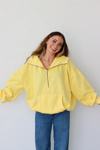 Woman wearing a yellow pullover with a zipper against a white background