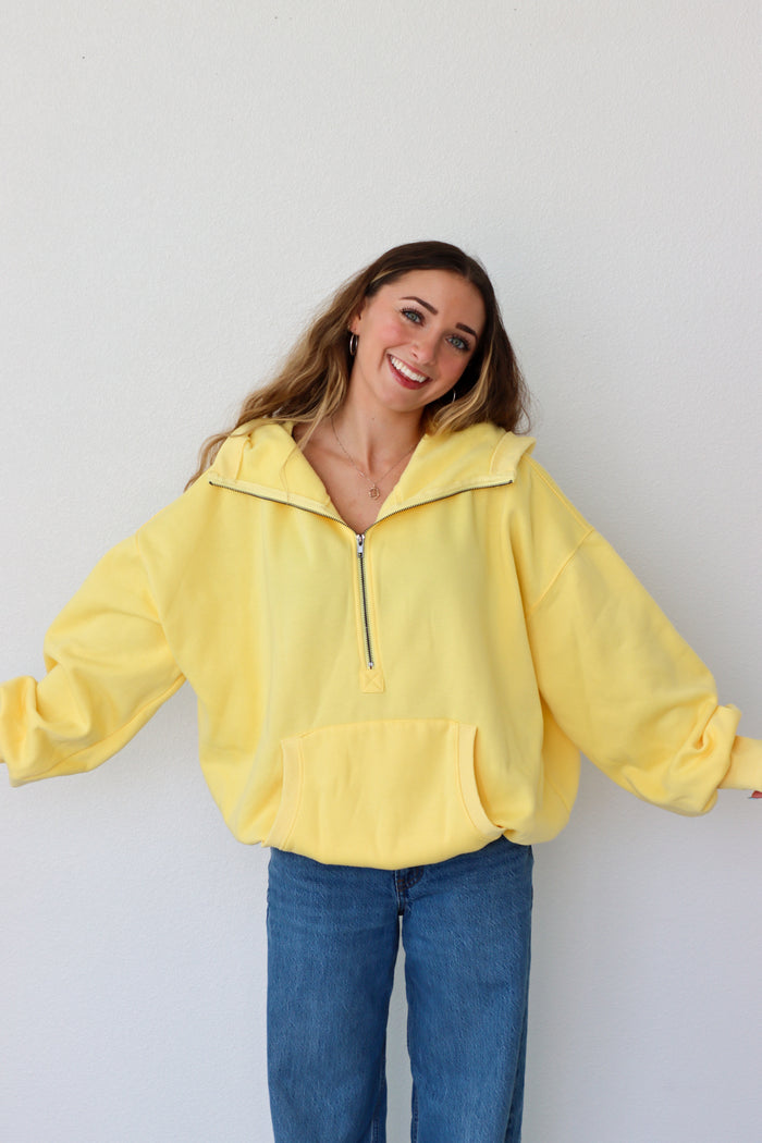 Woman wearing a yellow pullover with a zipper against a white background