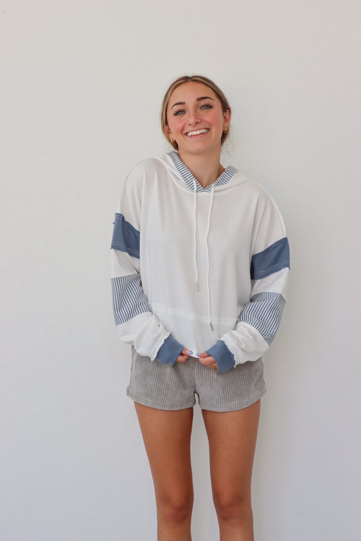 girl wearing white hoodie with blue sleeve detailing