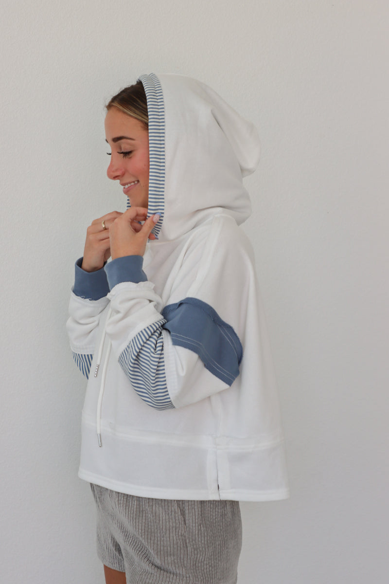 girl wearing white hoodie with blue sleeve detailing