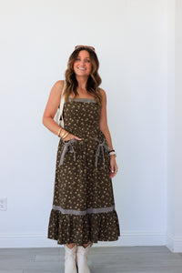 Woman wearing a patterned dress standing against a white wall.