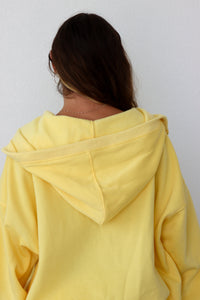 Person wearing a yellow hoodie with a plain background