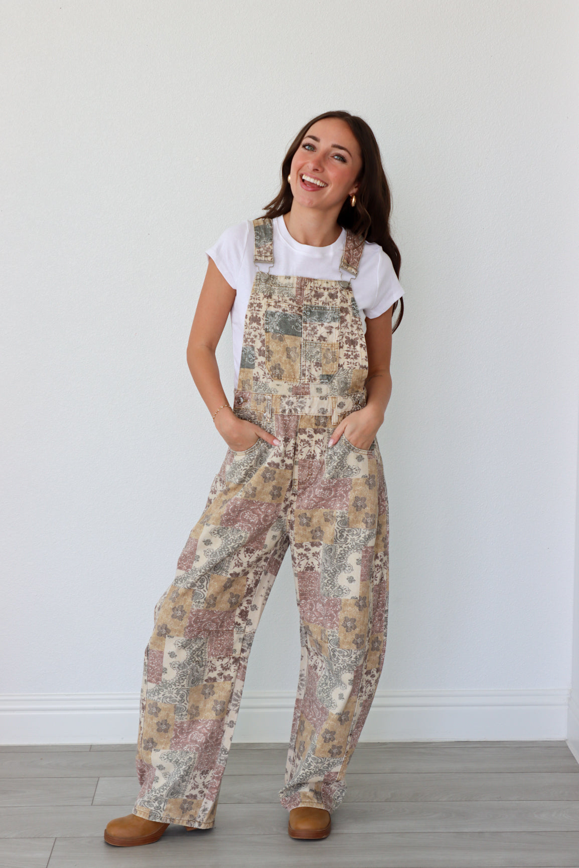 Woman wearing overalls and white t-shirt against a plain background