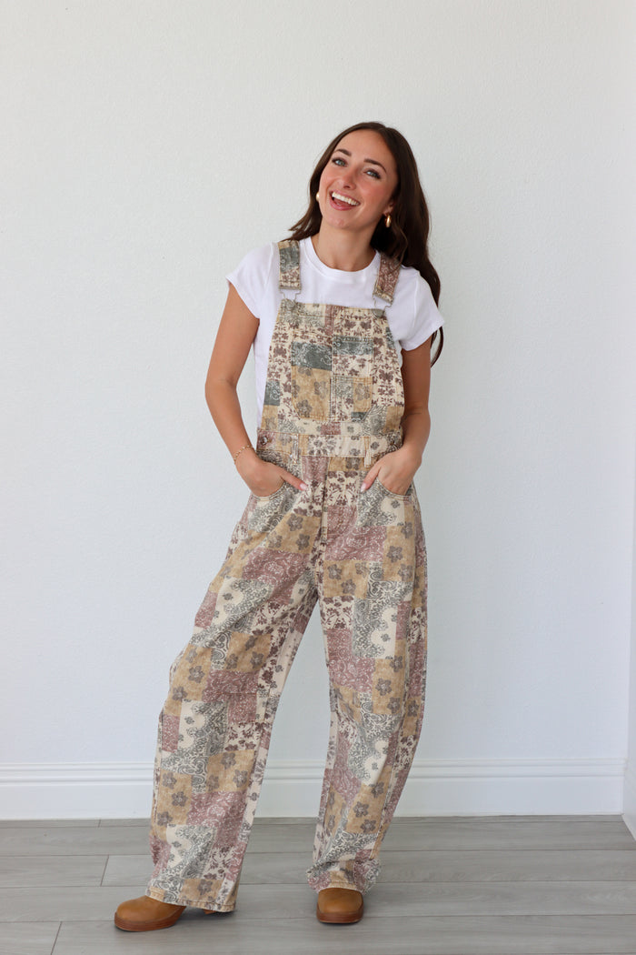 Woman wearing overalls and white t-shirt against a plain background