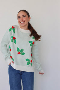 girl wearing white and green holly sweater