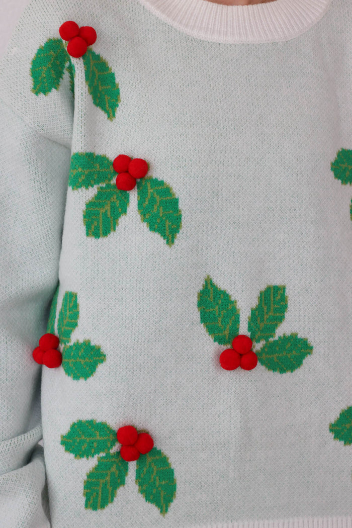 girl wearing white and green holly sweater