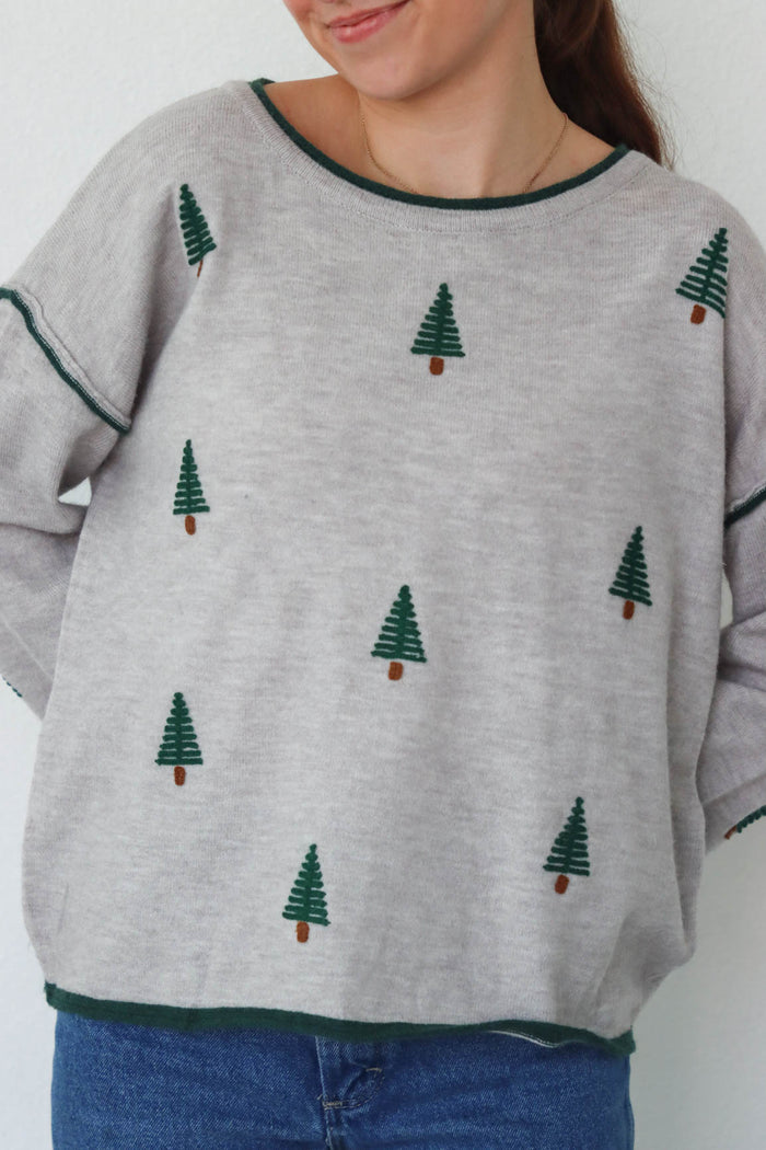 girl wearing gray pine tree sweater