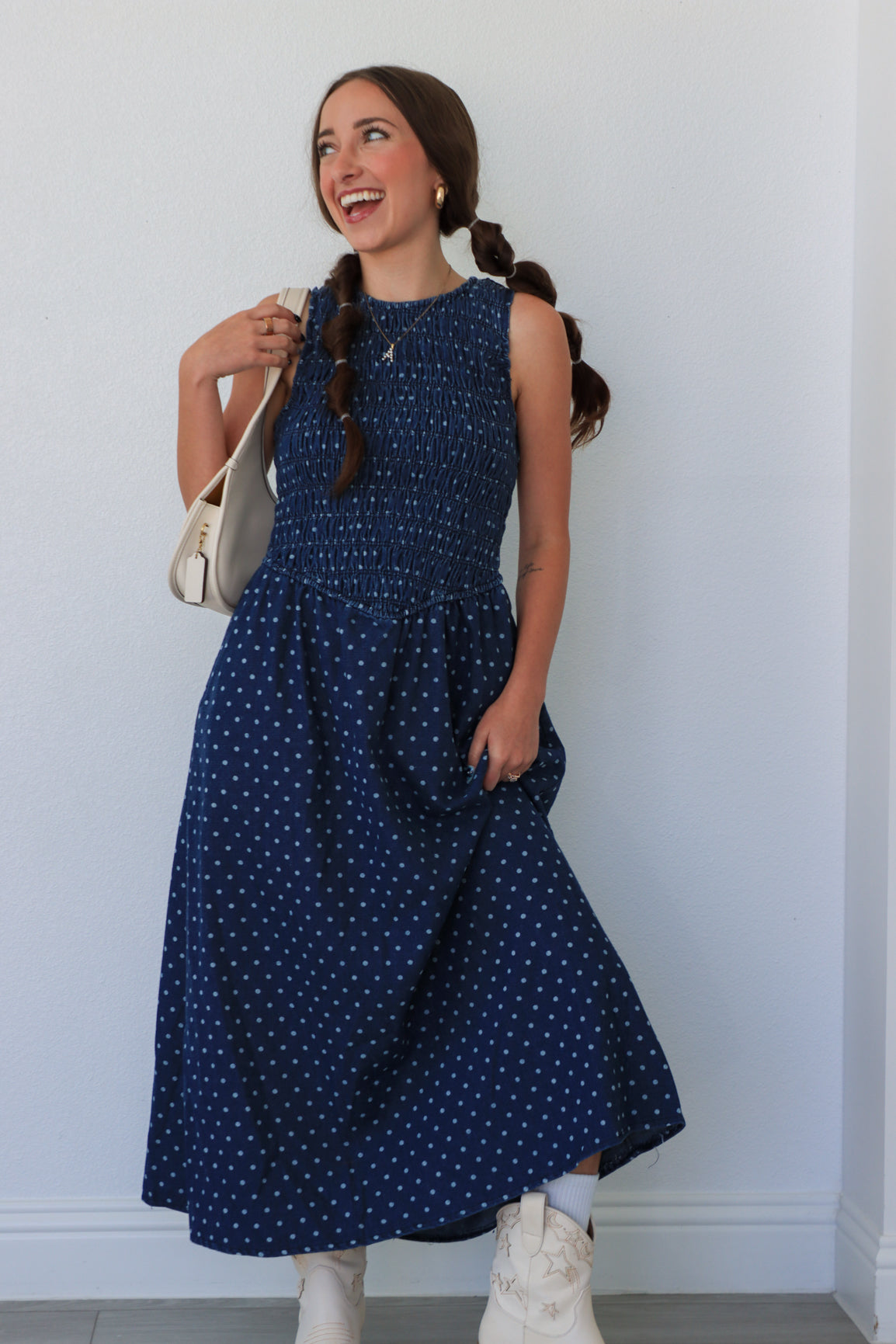 Woman wearing a blue polka dot dress against a white wall