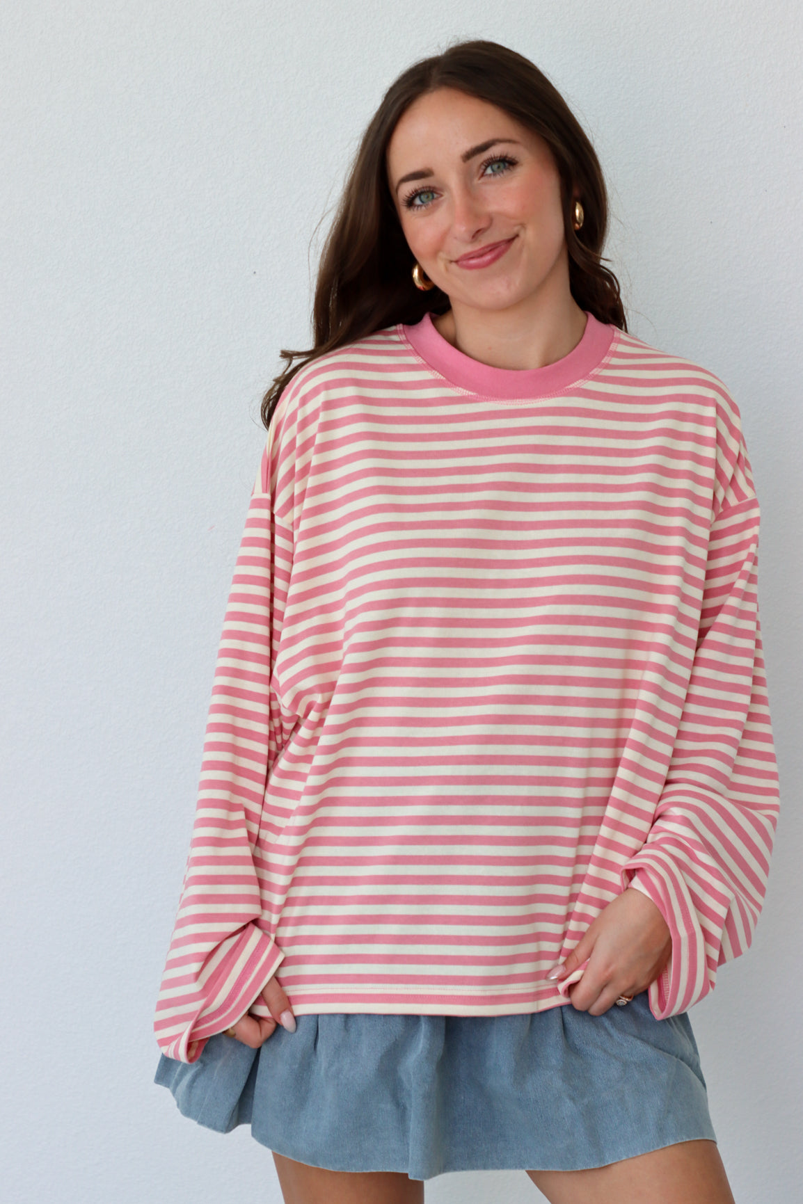 Woman wearing a pink and white striped shirt with a plain background